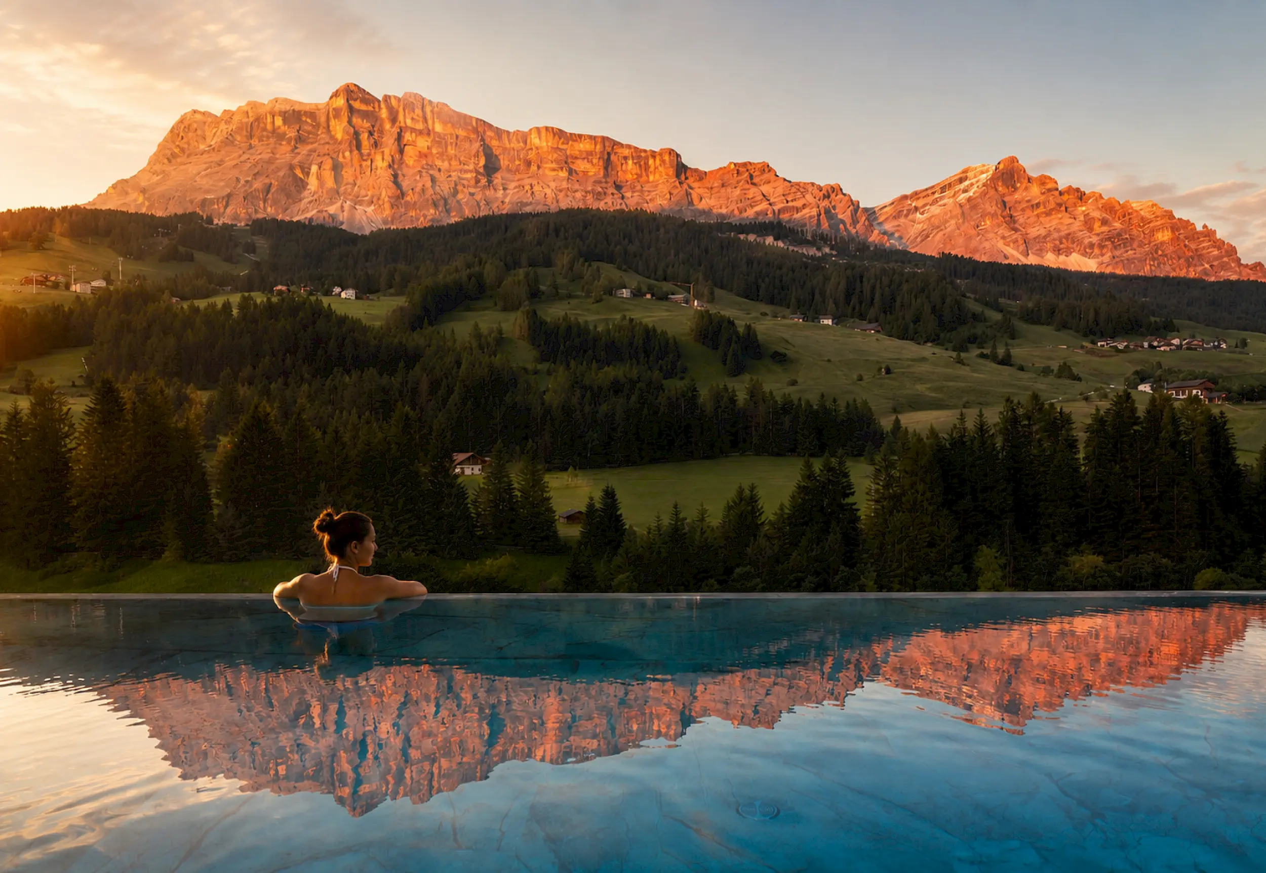Rooftop Infinity-Pool im Hotel Badia Hill im Abendrot, der Heiligkreuzkofel spiegelt sich im Wasser