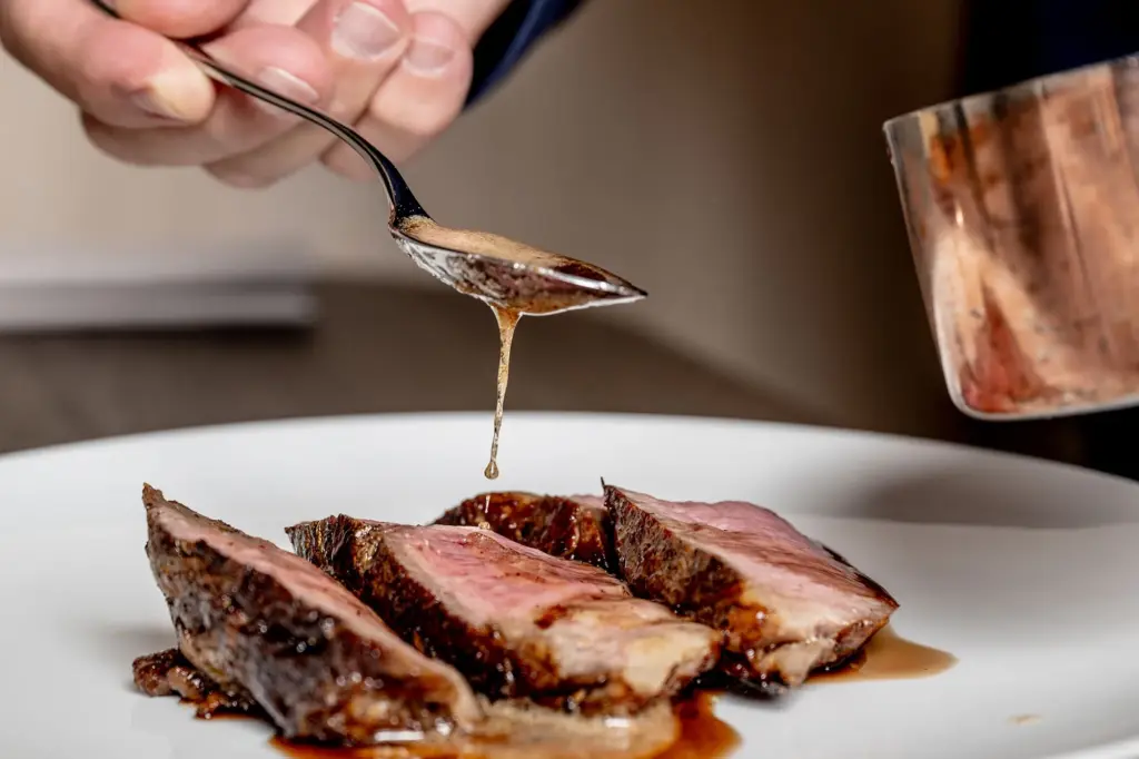 Fleisch wird mit Sauce angerichtet